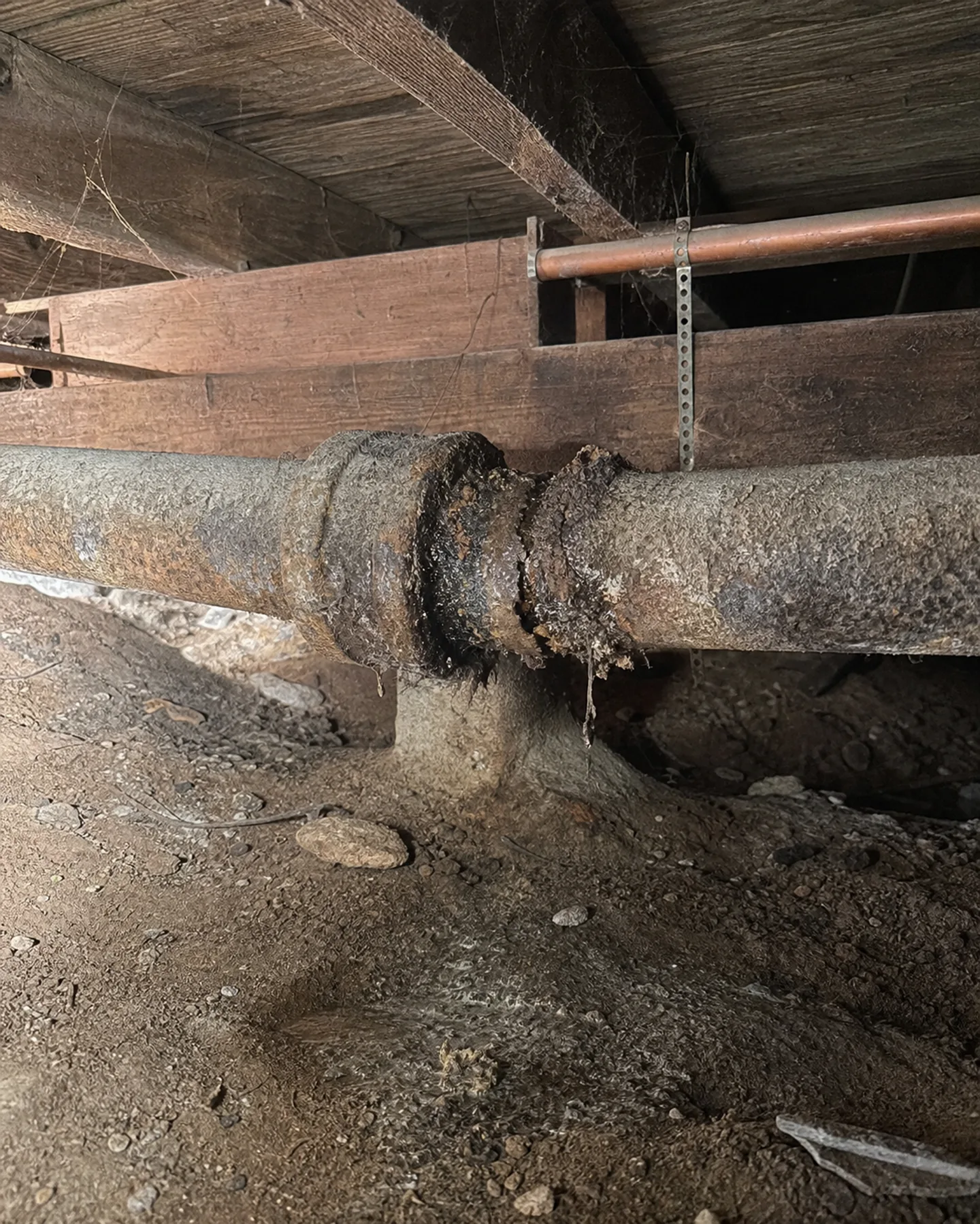 Cross-section of a cracked cast iron drain pipe with heavy internal rust buildup