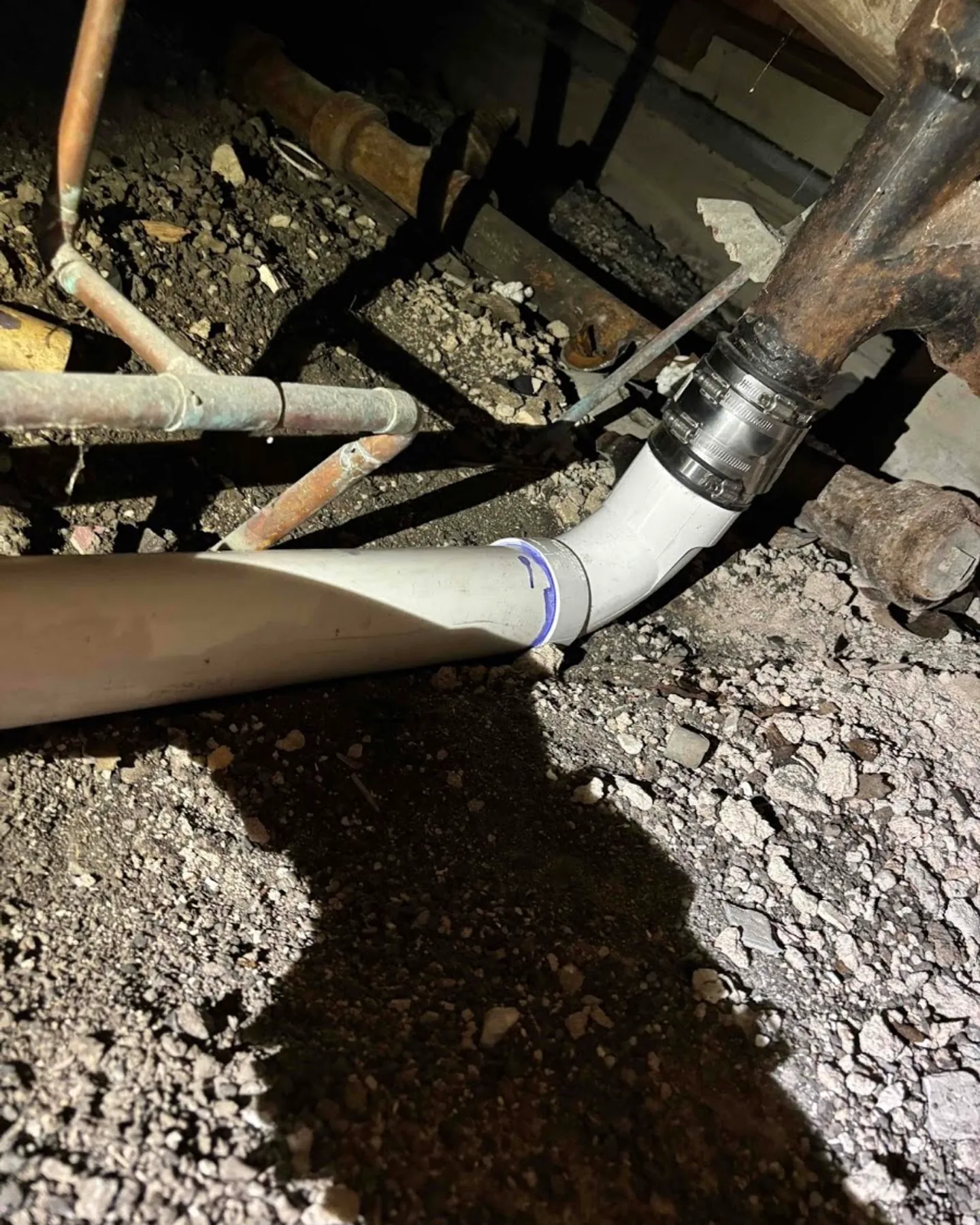 Cast iron drain line transitioned to new PVC piping beneath an older home