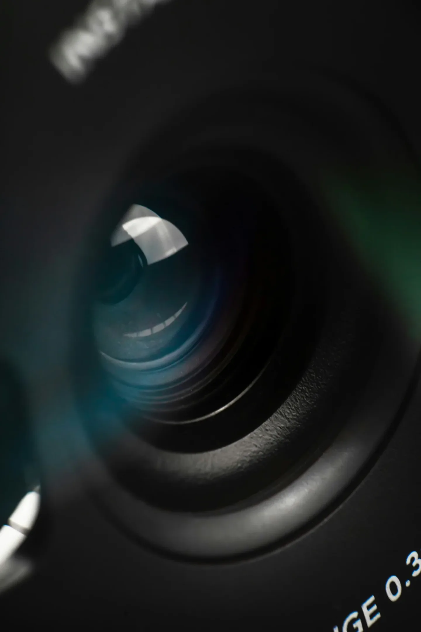 Close-up of a camera lens reflective surface with partial text showing on the lens rim.